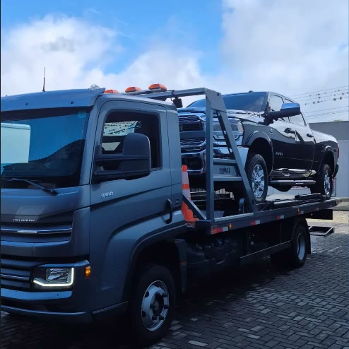 Caminhão plataforma da Star Veículos levando uma picape